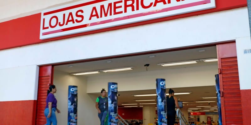 Fachada de uma loja das Lojas Americanas, com o letreiro vermelho e clientes passando pela entrada