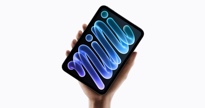 Mão segura o novo iPad mini com uma arte colorida em azul e roxo na tela, sobre fundo branco
