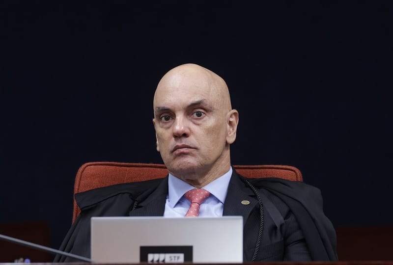 Alexandre de Moraes, de toga, sentado na bancada da Primeira Turma do STF, atrás de um notebook