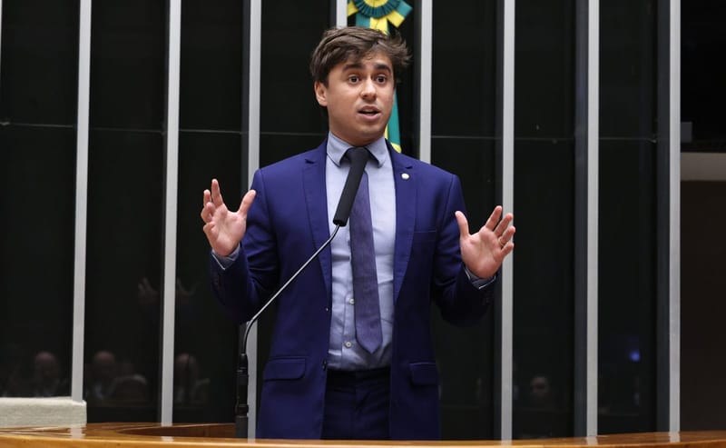 Nikolas Ferreira, de terno azul e gravata, gesticula diante do microfone da tribuna da Câmara