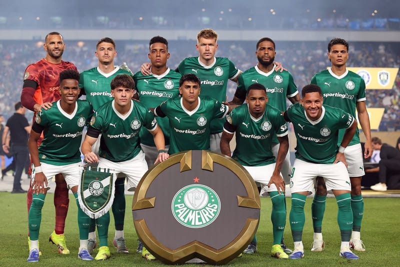 Onze jogadores do Palmeiras de uniforme verde, em duas fileiras diante de um troféu, posam em campo antes do jogo