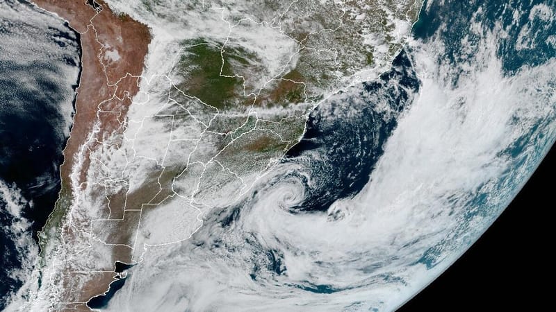 Imagem de satélite em cores naturais do Sul da América do Sul com um redemoinho de nuvens brancas sobre o oceano, perto do litoral gaúcho