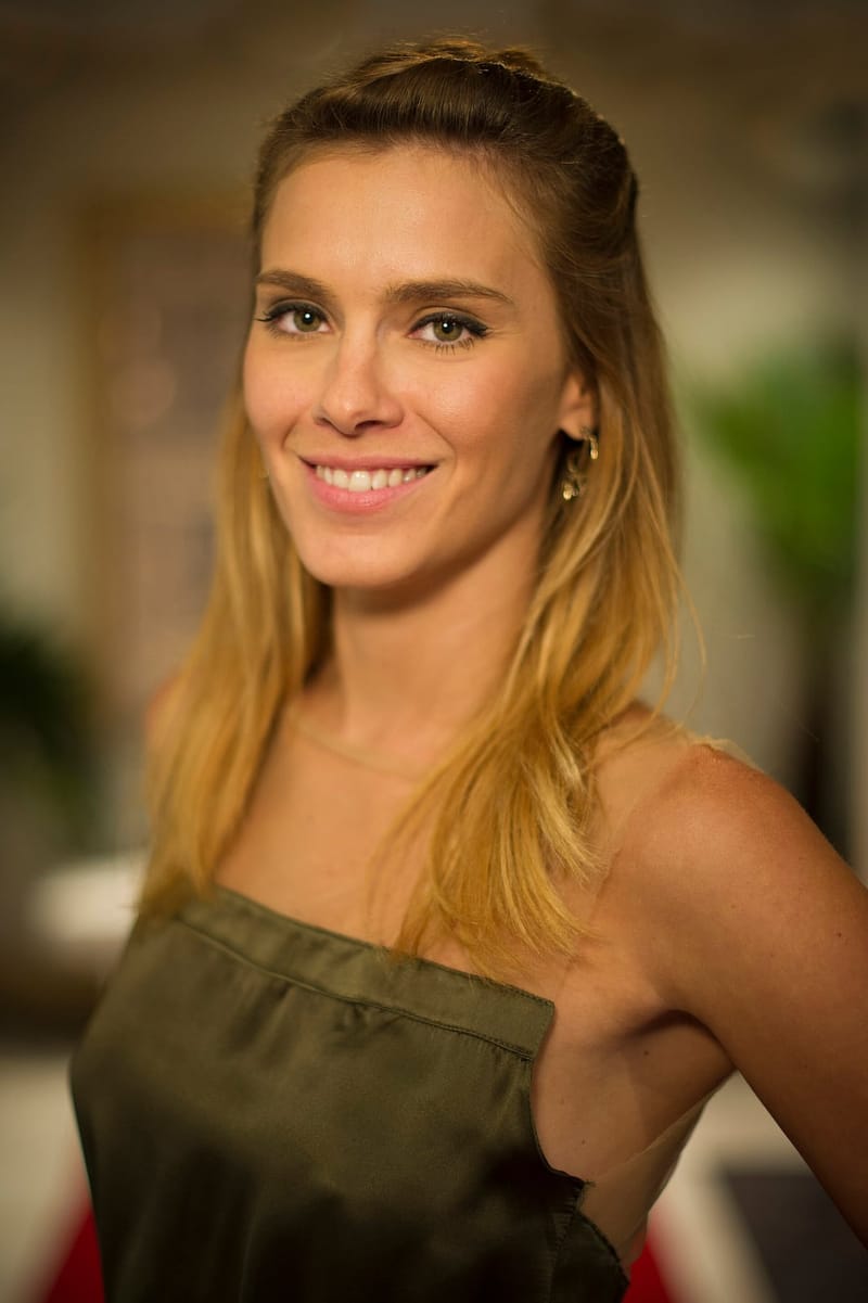 Retrato da atriz Carolina Dieckmann sorrindo, de cabelos loiros soltos e top verde