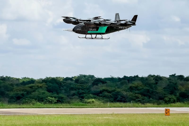 Protótipo do eVTOL da Eve, empresa ligada à Embraer, em voo baixo sobre uma pista, com mata ao fundo