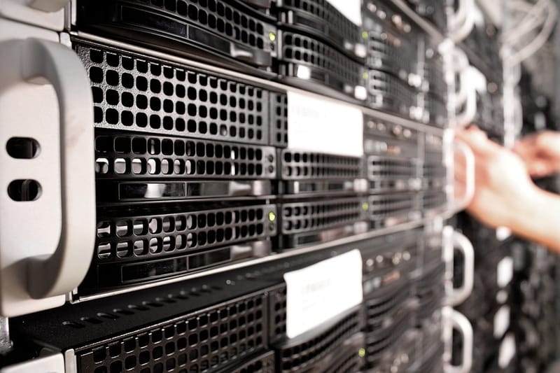 Fileiras de servidores em um rack de centro de dados, com a mão de um técnico ao fundo