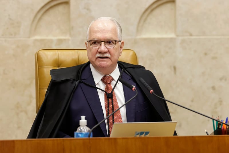 Edson Fachin, de óculos e toga preta, sentado na cadeira da presidência do plenário do Supremo, diante de microfones e um notebook