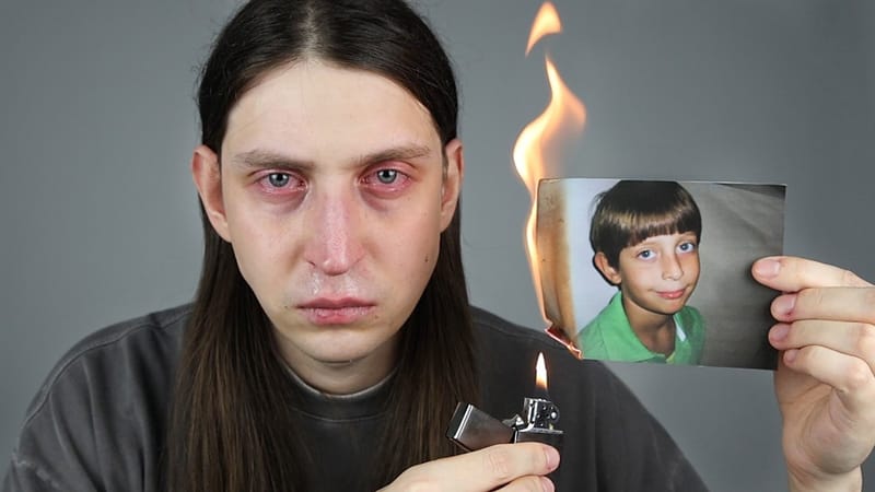 Felca, de cabelos longos e olhos vermelhos, segura um isqueiro aceso e uma foto antiga de si mesmo em chamas