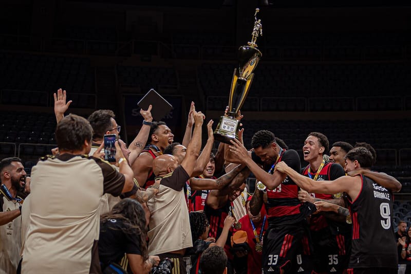 Jogadores do Flamengo erguem a taça de campeão carioca de basquete e comemoram com a comissão técnica no Maracanãzinho