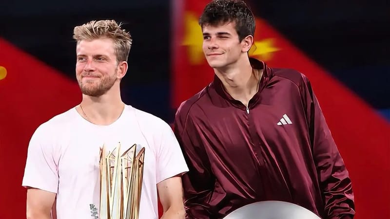 Davidovich Fokina, de camiseta branca, segura o troféu dourado e flores ao lado de Rafael Jódar, de agasalho vinho, que segura a bandeja prateada do ATP 1000, diante da bandeira da China