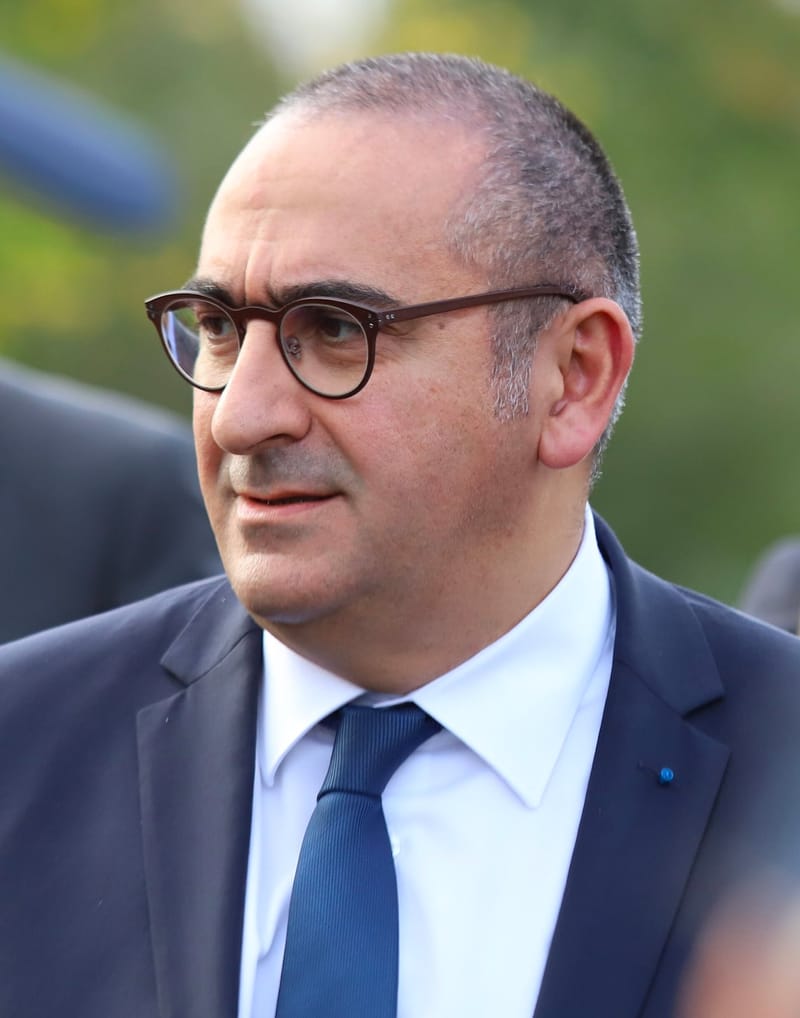 Laurent Nuñez, de óculos de armação marrom, terno azul-marinho e gravata azul, olha para a esquerda ao ar livre