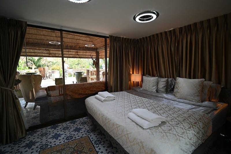 Quarto de dormir com cama de casal arrumada, luz baixa e cortinas