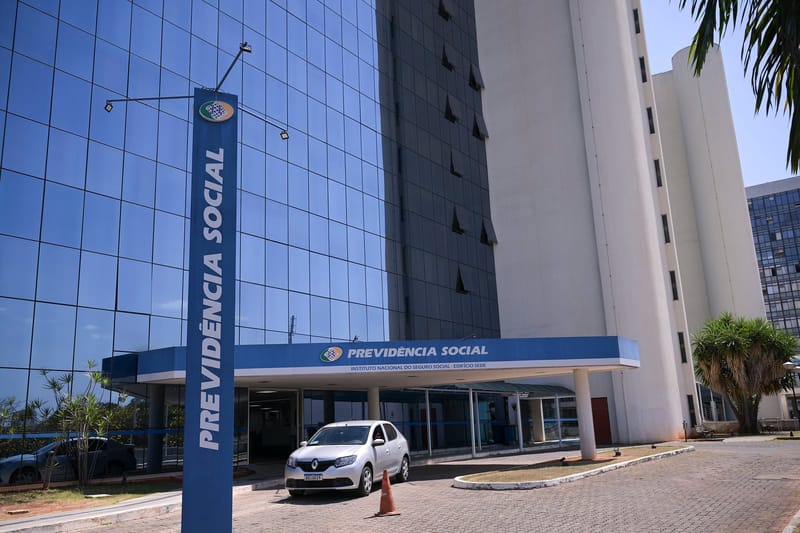 Entrada do edifício-sede do INSS, com a placa azul da Previdência Social e fachada de vidro