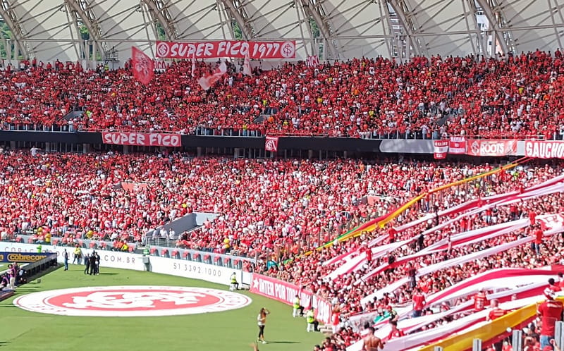 Arquibancadas do Beira-Rio lotadas de torcedores de vermelho, com faixas e o escudo do Internacional no gramado