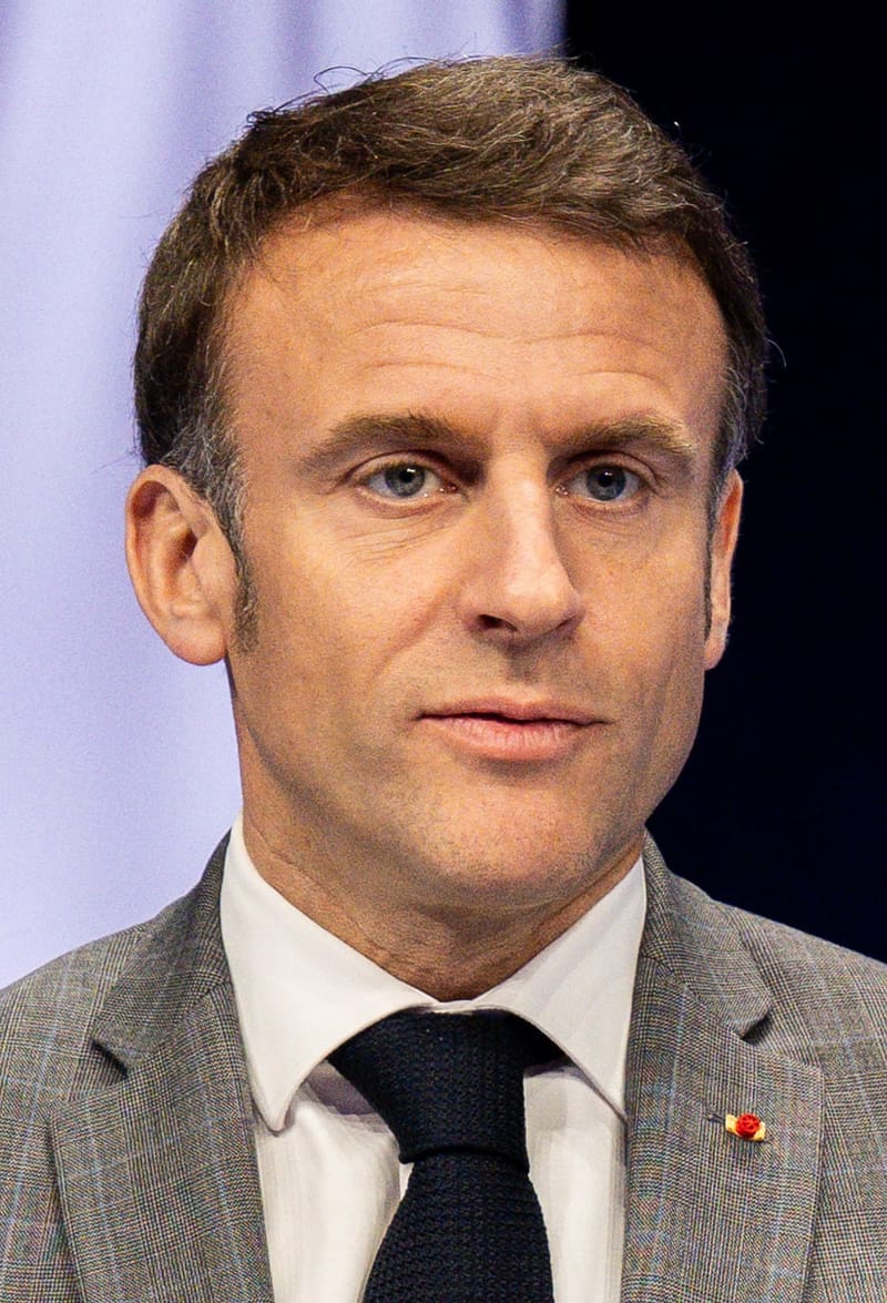 Emmanuel Macron, de terno cinza e gravata escura, olha para a frente durante evento