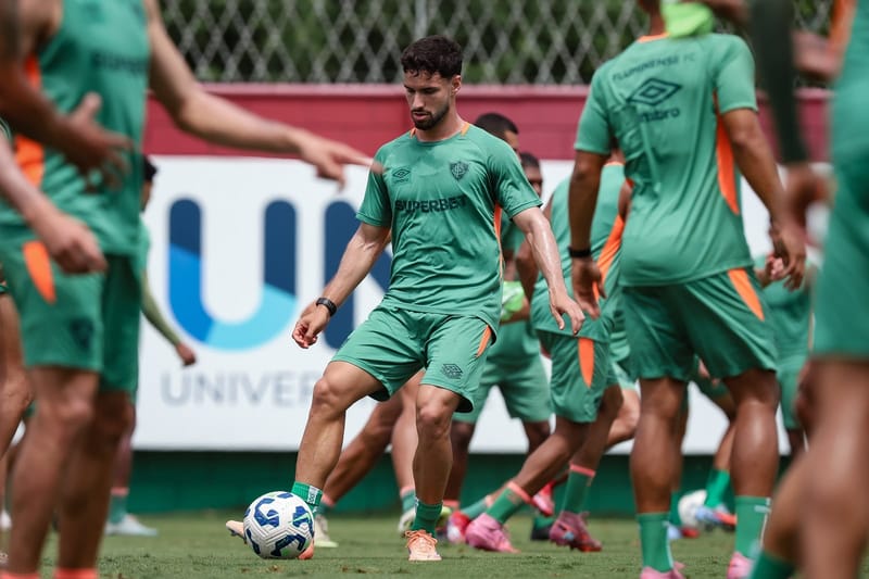 Martinelli, de camisa verde do Fluminense, domina a bola durante treino, cercado por companheiros