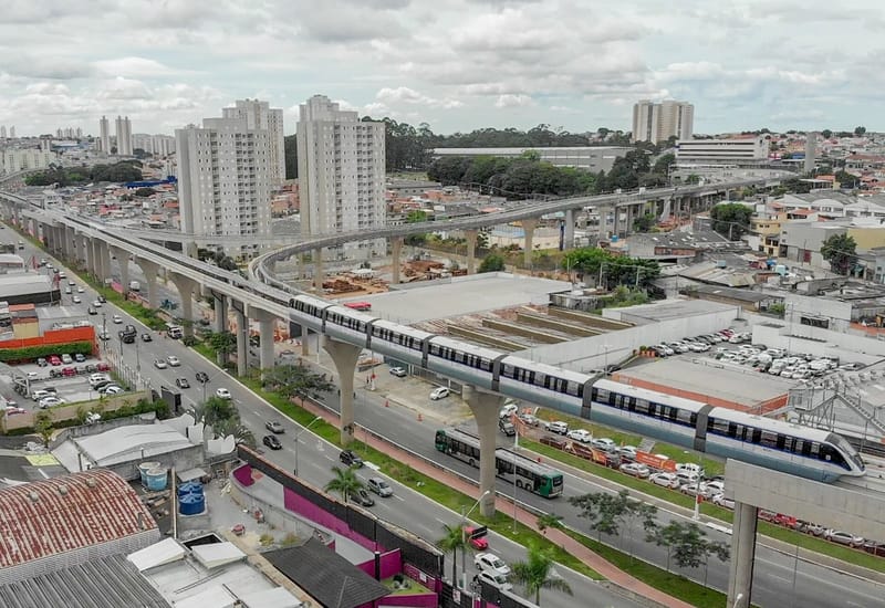 Trem do monotrilho da Linha 15-Prata sobre a via elevada, em avenida da zona leste de São Paulo, com prédios ao fundo