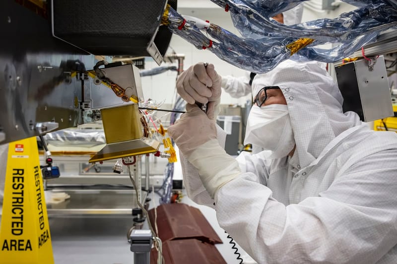 Técnico de roupa de sala limpa instala uma câmera dourada de navegação na aeronave Dragonfly