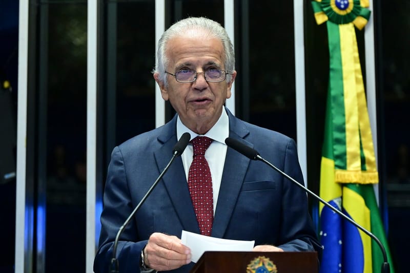 O ministro da Defesa, José Múcio Monteiro, de terno azul e óculos, discursa na tribuna do Senado ao lado da bandeira do Brasil
