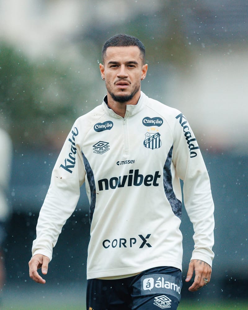 O meia Philippe Coutinho, com agasalho branco do Santos, caminha em treino sob chuva fina