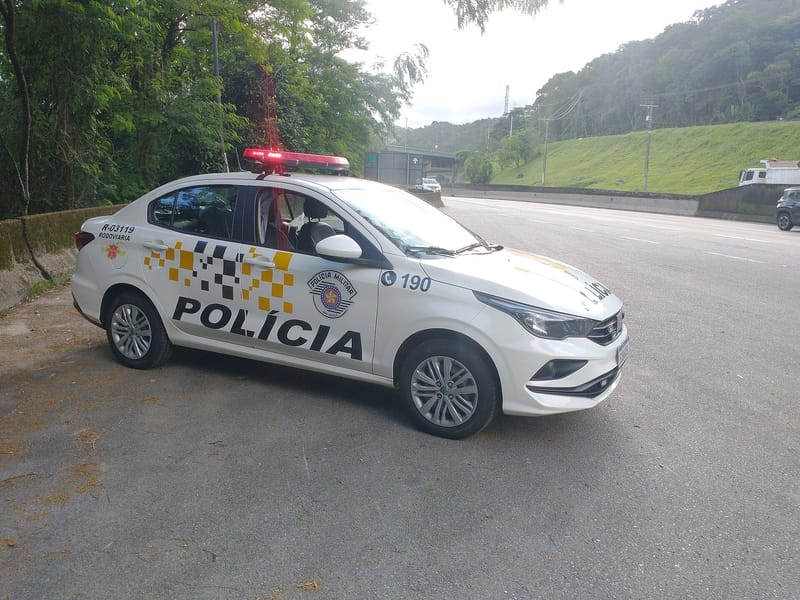 Viatura branca da Polícia Militar de São Paulo, com a inscrição Polícia e o número 190, estacionada à beira de uma rodovia