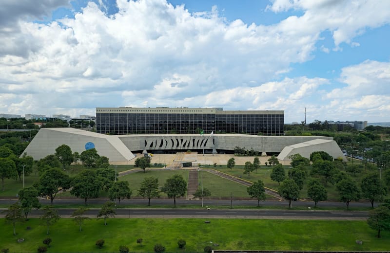 Vista aérea do edifício-sede do Superior Tribunal de Justiça, em Brasília, sob céu azul com nuvens