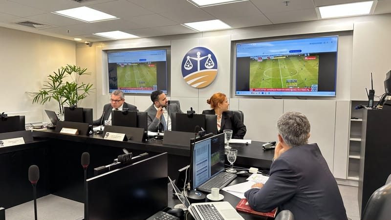 Auditores da Quarta Comissão Disciplinar do STJD durante sessão de julgamento, com o logotipo do tribunal ao fundo