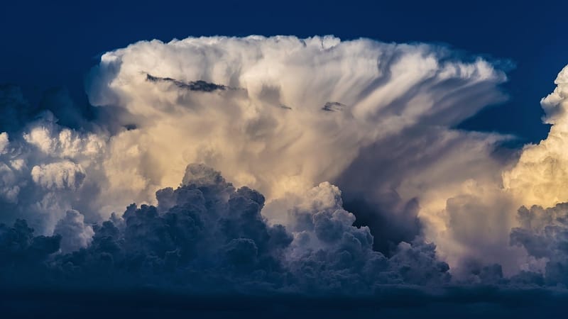 Enorme nuvem branca de tempestade, em forma de bigorna, contra o céu azul escuro