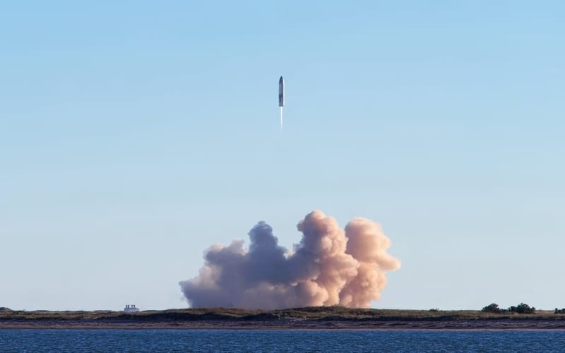 Foguete da SpaceX em voo de teste, subindo sobre uma nuvem de fumaça rosada perto do mar