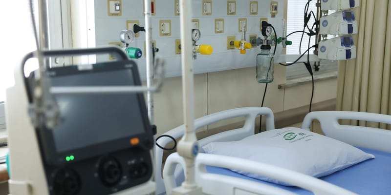 Leito de UTI com cama hospitalar, monitor, bombas de infusão e réguas de gases na parede