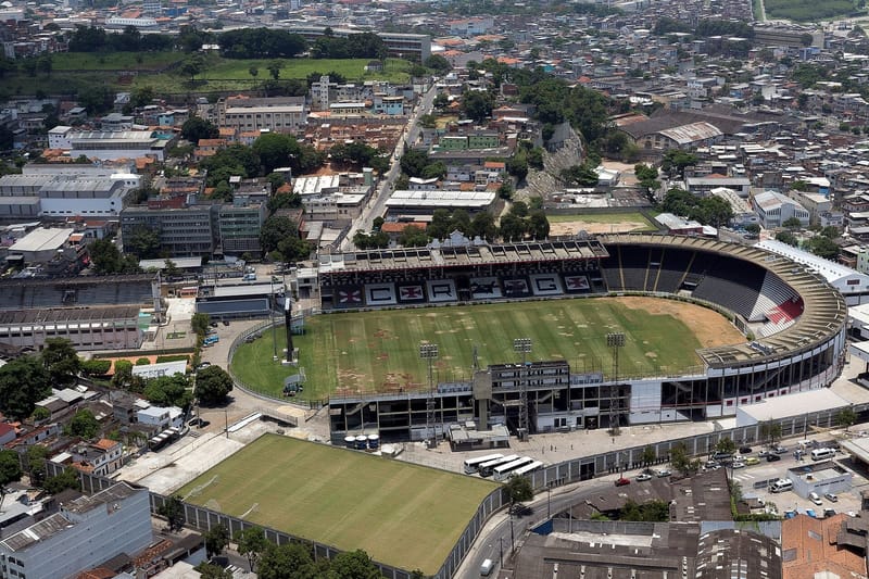 Vista aérea do estádio de São Januário, com o gramado verde, as arquibancadas e o casario do entorno, no Rio de Janeiro
