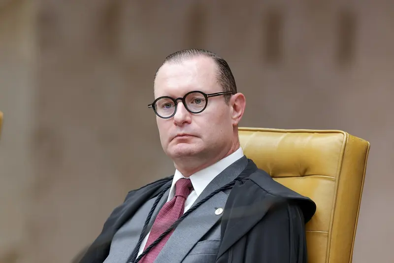 Cristiano Zanin, de óculos redondos de aro preto e toga, sentado na poltrona dourada do plenário, olha de frente com expressão séria