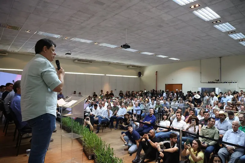 Tarcísio de Freitas, de camisa verde-clara e microfone na mão, fala em um púlpito diante de uma plateia numerosa em um auditório