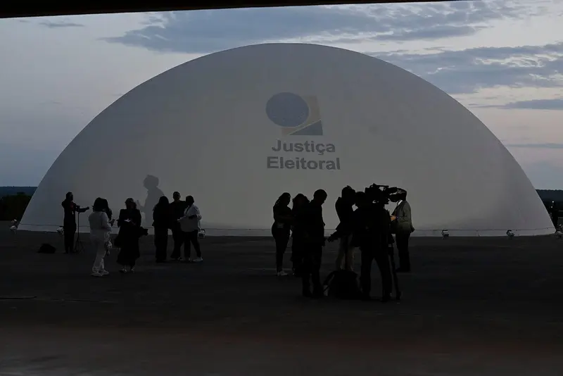 Cúpula da Justiça Eleitoral, no TSE, ao entardecer, com jornalistas e cinegrafistas em silhueta à frente