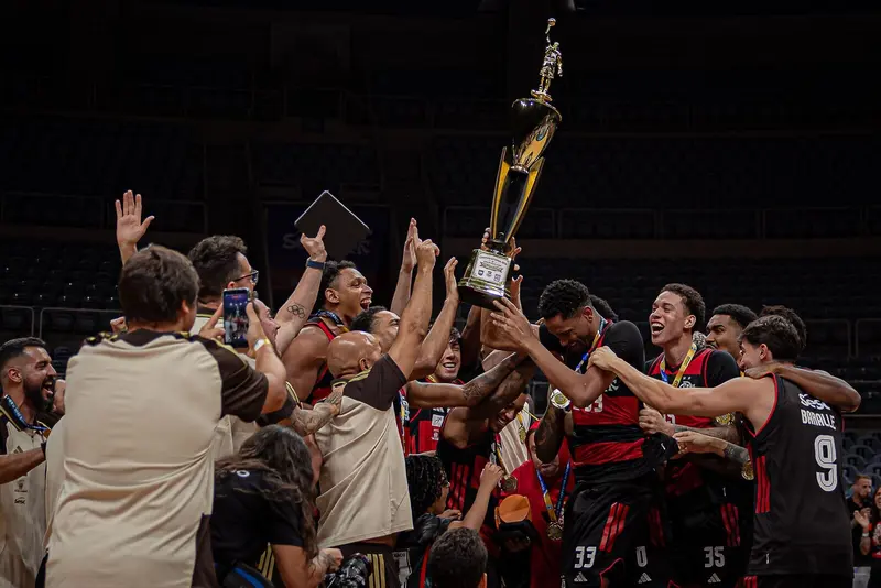 Jogadores do Flamengo erguem a taça de campeão carioca de basquete e comemoram com a comissão técnica no Maracanãzinho