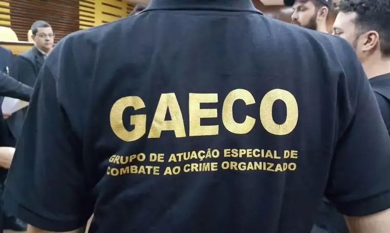 Agente de costas veste camiseta preta do Gaeco, grupo de combate ao crime organizado