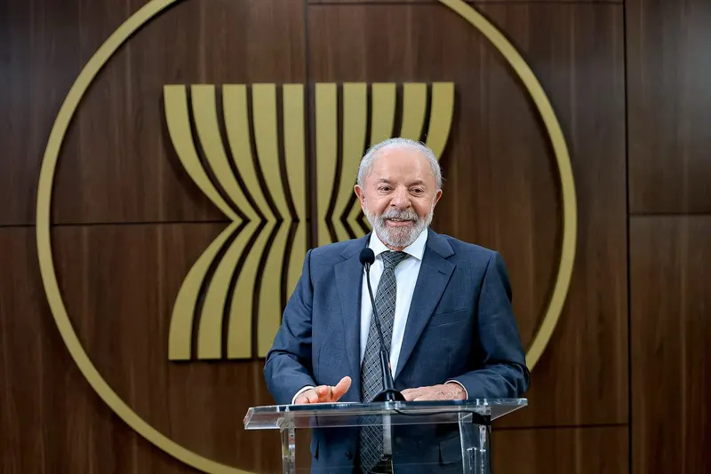 O presidente Luiz Inácio Lula da Silva discursa em um púlpito de acrílico, diante de um painel de madeira