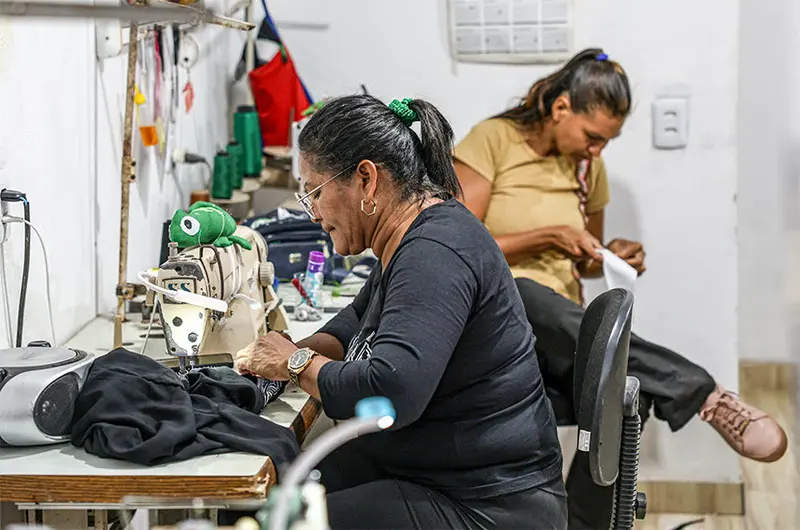 Costureiras trabalham em máquinas de costura em uma pequena oficina