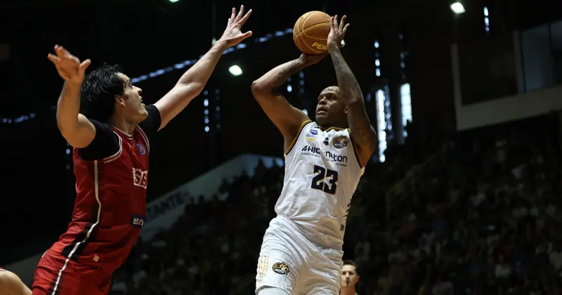 Jogador do Mogi, de camisa branca número 23, arremessa sobre a marcação de um adversário de camisa vermelha em jogo da final do Paulista