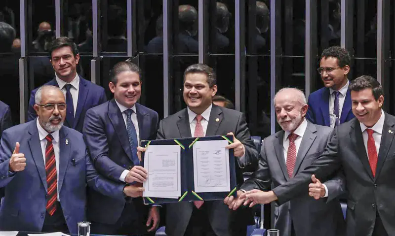 Davi Alcolumbre segura a emenda constitucional assinada, ao lado de Hugo Motta e de Lula, na sessão de promulgação no plenário do Senado