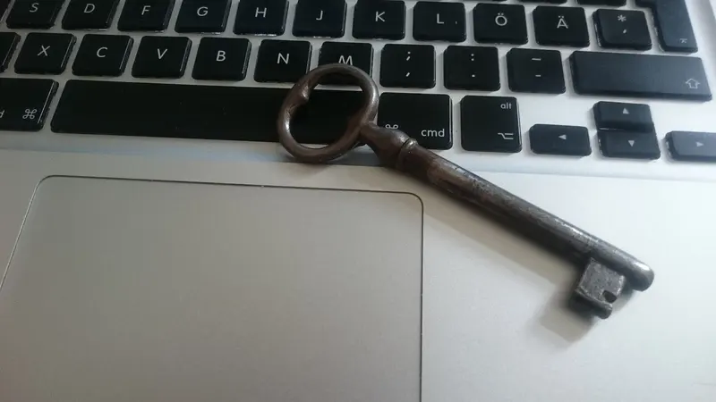 Chave antiga de metal apoiada sobre o teclado de um notebook prateado